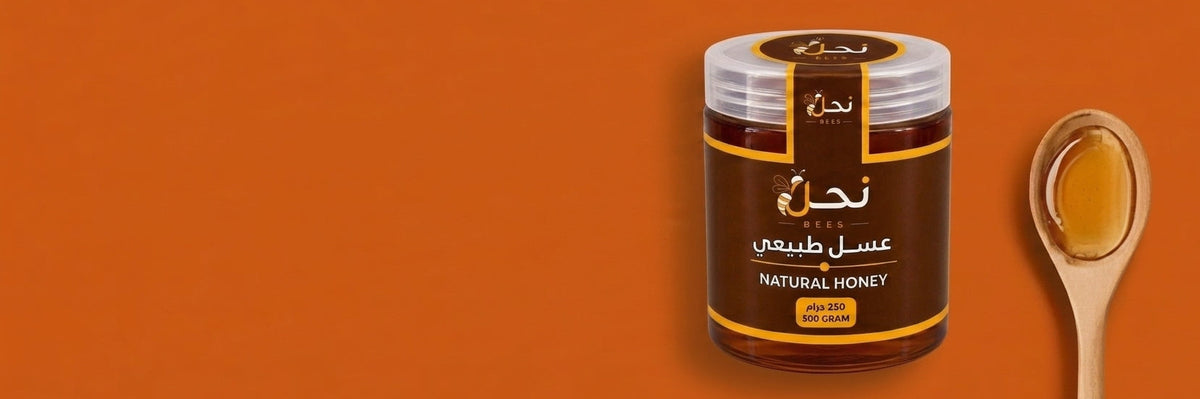A jar of natural honey with a wooden spoon filled with honey, set against a solid orange background. The jar features a dark brown label with gold accents and Arabic text.